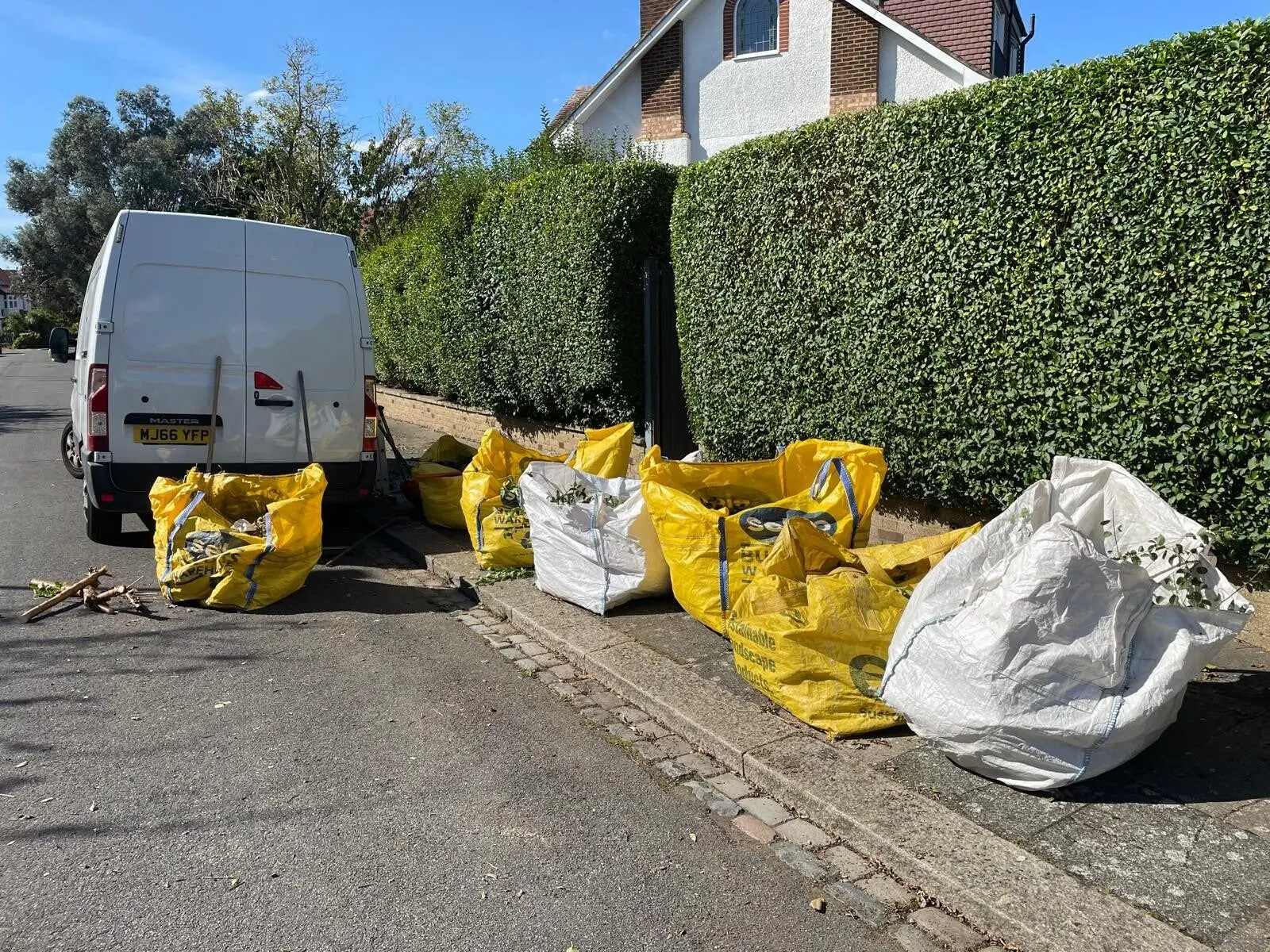 Hedge cut back hard with the waste bagged beside the van for removal